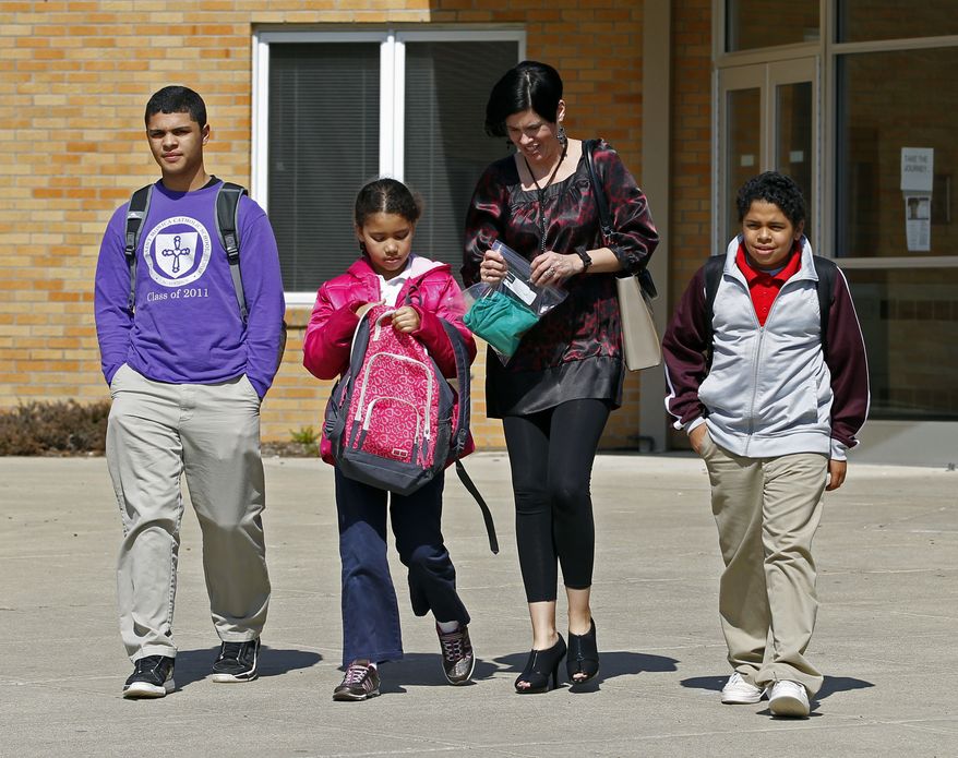 ** FILE ** In this March 16, 2011 photo, Heather Coffy, right center, leaves the St. Monica School in Indianapolis with her children, left to right, Delano Coffy, 15, Alanna Marshall, 8, and Darius Coffy, 11. Students like Delano are at the heart of brewing political fights and court battles over whether public dollars should go to vouchers to help make private schools more affordable. (AP Photo/Michael Conroy, File)
