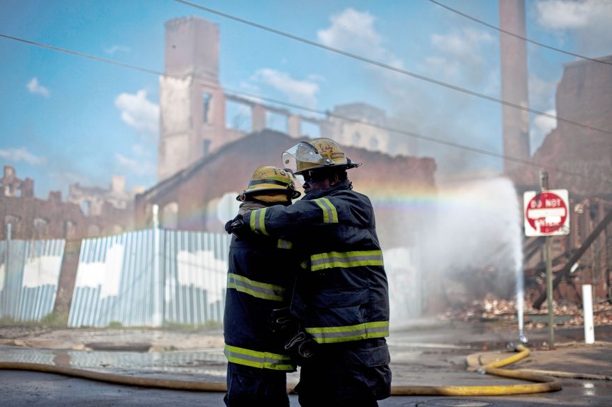 Firefighters greet each other in the aftermath of a fire Monday morning in a warehouse in Philadelphia that killed two firefighters. (Associated Press)