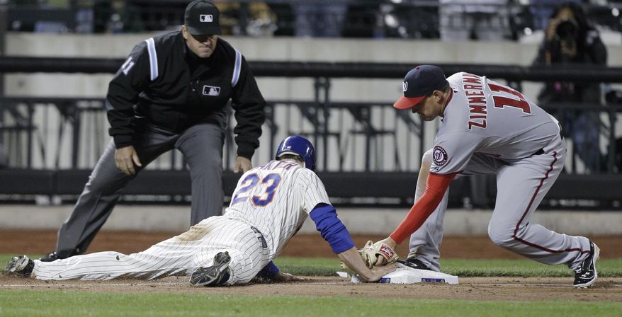New York Mets' Mike Baxter is safe sliding back to third after advancing on Ruben Tejada's ninth-inning sacrifice bunt, as Washington Nationals third baseman Ryan Zimmerman applies a late tag and third base umpire Tony Randazzo watches in the Mets' 4-3 victory in a baseball game in New York, Monday, April 9, 2012. Baxter later scored on Daniel Murphy's single. (AP Photo/Kathy Willens)