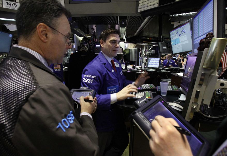 Specialist Robert Tuccillo (center) works with traders on the floor of the New York Stock Exchange on Monday, April 9, 2012. Stocks opened sharply higher on Wednesday, a day after their worst loss of the year. (AP Photo/Richard Drew)