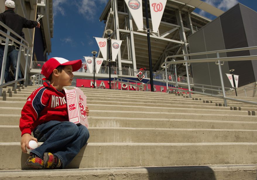 Ethan Martinez, 3, of Reston, decked out in Nationals gear, enjoys a box of popcorn outside the ballpark. (Andrew Harnik/The Washington Times)
