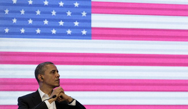 President Barack Obama sits in front of a large video screen displaying an image of a U.S. national flag at the CEO Summit of the Americas, in Cartagena, Colombia, Saturday April 14, 2012. (AP Photo/Carolyn Kaster)