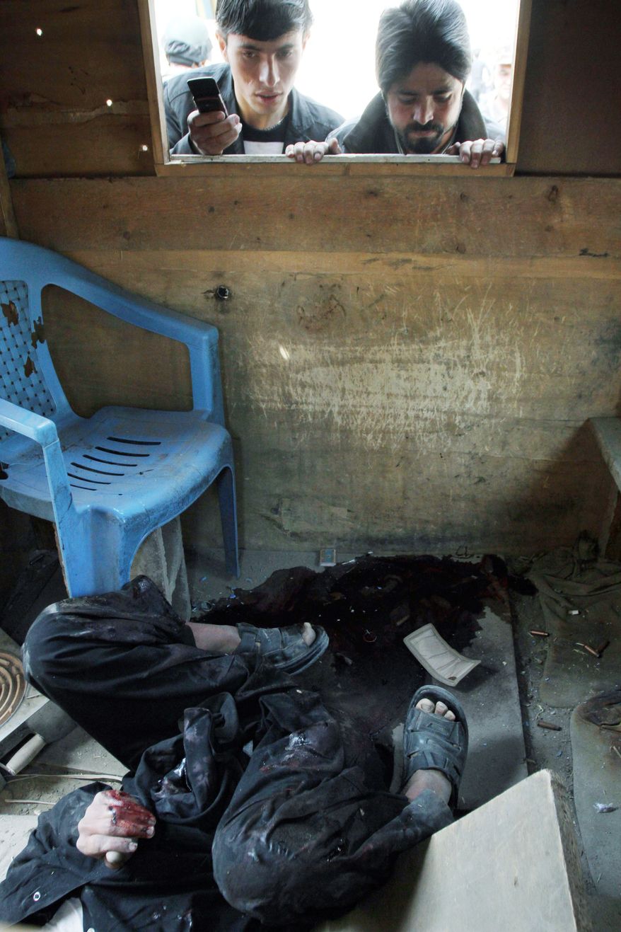 Afghans examine the body of a militant who was shot at a security booth after a gunbattle in Kabul on Monday. A brazen, 18-hour Taliban attack on the Afghan capital ended early Monday when insurgents who had holed up overnight in two buildings were overcome by heavy gunfire from Afghan-led forces and pre-dawn air assaults from U.S.-led coalition helicopters.