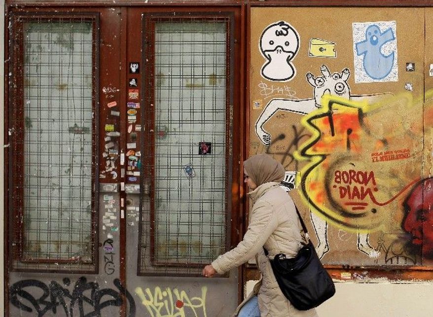 ASSOCIATED PRESS
A woman walks past a closed store in Madrid on Saturday. Spain is back in the center of the eurozone debt crisis as the interest rate on its government bonds rose Monday to their highest level since December, a sign that investors are becoming more concerned about the country's ability to afford its debts.