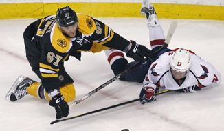 Washington Capitals defenseman Mike Green (right) tries to get a stick on the puck after being dropped to the ice by Boston Bruins left wing Benoit Pouliot during the third period of the Capitals&#x27; 2-1 victory in Game 2 of their first-round playoff series in Boston on April 14, 2012. (Associated Press)