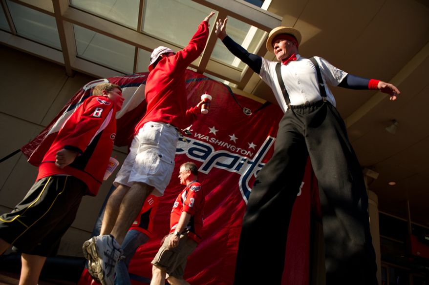 Mike Beck, second from left, jumps up to high five stilt entertainer Mark Lohr, right, before the Washington Capitals take on the Boston Bruins in game three of National Hockey League first round playoff hockey at the Verizon Center, Washington, D.C., Monday, April 16, 2012. (Andrew Harnik/The Washington Times)