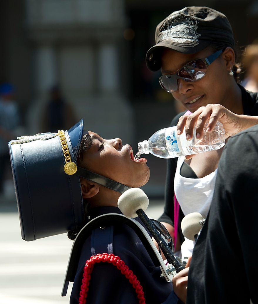 Caprice Casson offers cool water to Dana Treece, 10, a young drummer in the JC Nalle Elementary School band, as they make they way along Pennsylvania Avenue NW during the District of Columbia Emancipation Day 2012 parade in Washington, D.C., Monday, April 16, 2012., celebrating the150th anniversary of the District of Columbia Emancipation Act. 150 ears ago, on April 16, 1862, President Abraham Lincoln signed a bill ending slavery in the District of Columbia. Passage of this law came 8 1/2 months before President Lincoln signed his Emancipation Proclamation. (Rod Lamkey Jr/The Washington Times)