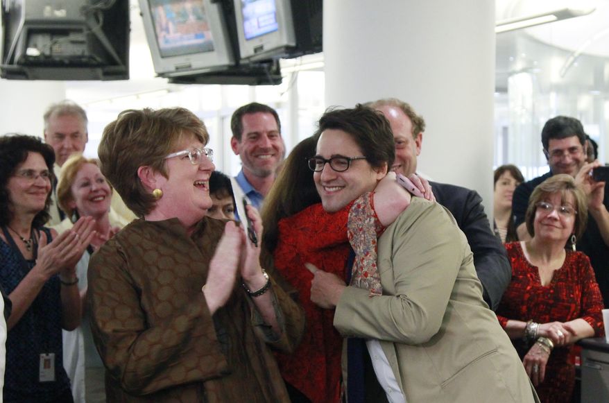 Associated Press executive editor Kathleen Carroll (left) applauds April 16, 2012, as AP reporter Adam Goldman (center) is hugged after winning the Pulitzer Prize for Investigative Reporting with three colleagues in New York. They revealed a secret New York Police Department program that spied on Muslim neighborhoods. (Associated Press)