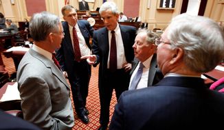 Senate Minority Leader Richard L. Saslaw (center), Fairfax Democrat, talks with Senate Majority Leader Thomas K. Norment Jr. (left), James City Republican, as Sen. Emmett Hanger (second from left), Augusta Republican, and Sen. Charles Colgen (second from right), Prince William Democrat, and Finance Committee Chairman Sen. Walter Stosch, Henrico Republican, listen prior to the debate on the budget conferees&#39; report at the Capitol in Richmond on Tuesday. (Associated Press)
