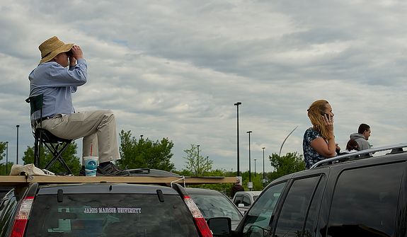 Dennis Smyers, left, of Reston, Va., sits on IKEA shelves on top of his car to get a better view of the space shuttle Discovery as it flies past the Smithsonian Air and Space Museum&#39;s Udvar-Hazy Center in Chantilly, Va., on Tuesday, April 17, 2012. At right, Cheryl Baker of Centreville, Va., peeks her head out of her sunroof to get a view too. (Barbara L. Salisbury/The Washington Times)