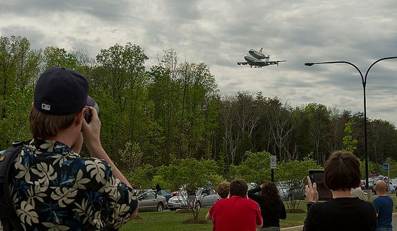 People photograph the Discovery as it flies past the Smithsonian Air and Space Museum Udvar-Hazy Center in Chantilly, Va., on Tuesday, April 17, 2012. The shuttle left the Kennedy Space Center Tuesday morning and flew around Washington, D.C. before finally landing at Washington Dulles International Airport. Discovery will now be towed over to the Udvar-Hazy center, where it will take the place of the Enterprise in a welcoming ceremony on Thursday. (Barbara L. Salisbury/The Washington Times)
