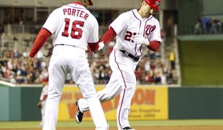 Washington Nationals third base coach Bo Porter congratulates Xavier Nady after he hit a home run during the eighth inning against the Cincinnati Reds on Friday, April 13, 2012, in Washington. The Nationals won 2-1 in 13 innings. (AP Photo/Evan Vucci)