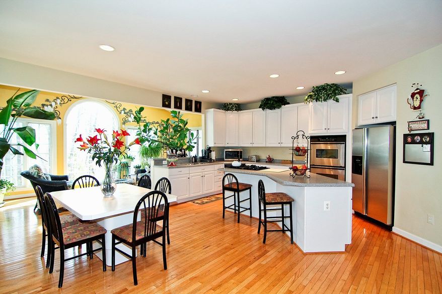 The eat-in kitchen, which features stainless steel appliances and Corain counters, opens into the sunroom.
