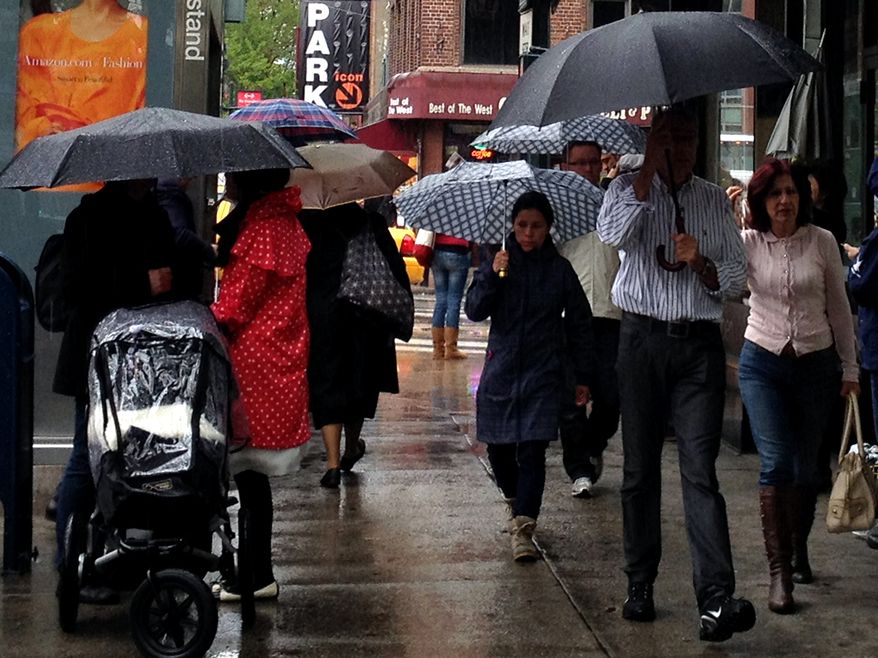 People walk with umbrellas in the rain along 9th Avenue in New York on April 22, 2012. (Associated Press)
