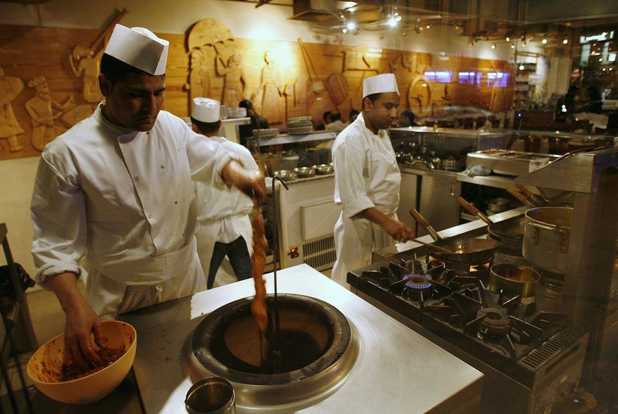 Cooks, seen through a restaurant window, work in the kitchen of a curry house near Brick Lane in east London, Wednesday, Feb. 13, 2008. Restaurant owners and immigrants' advocates say new government policies restricting the flow of workers from Bangladesh are causing a staffing crisis at Britain's thousands of curry houses. (AP Photo/Akira Suemori)