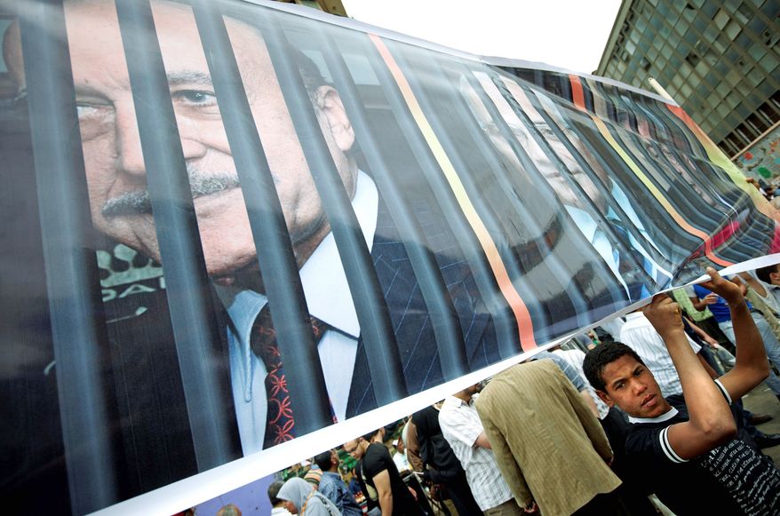 A protester holds a banner depicting one-time presidential candidates Omar Suleiman, Ahmed Shafik and Amr Moussa behind bars at a protest in Cairo's Tahrir Square on Friday. Of the three, only Mr. Moussa remains on the ballot; Mr. Suleiman and Mr. Shafik are among 11 disqualified by Egypt's electoral commission. (Associated Press)