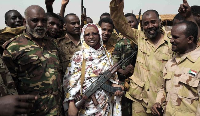 Sudanese state Minister of Information Sana Hamad poses April 24, 2012, for a photo with Sudanese armed forces at the oil-rich border town of Heglig, Sudan. (Associated Press)