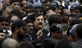 Pakistani Prime Minister Yousuf Raza Gilani (center), surrounded by guards, leaves the Supreme Court in  Islamabad on Thursday, April 26, 2012, after he was convicted of contempt for refusing to reopen an old corruption case against President Asif Ali Zardari. (AP Photo/Muhammed Muheisen)