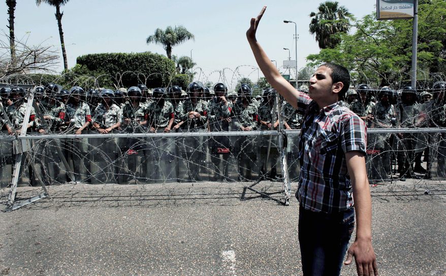 An Egyptian protester directs his fellow protesters away from the army security barrier blocking the road leading to the Ministry of Defense, in Cairo, Egypt Sunday, April 29, 2012. Assailants attacked demonstrators gathered outside the Defense Ministry in Egypt's capital to call for an end to military rule with rocks and firebombs, killing one protester and wounding scores, security officials said on Sunday. (AP Photo/Nasser Nasser)