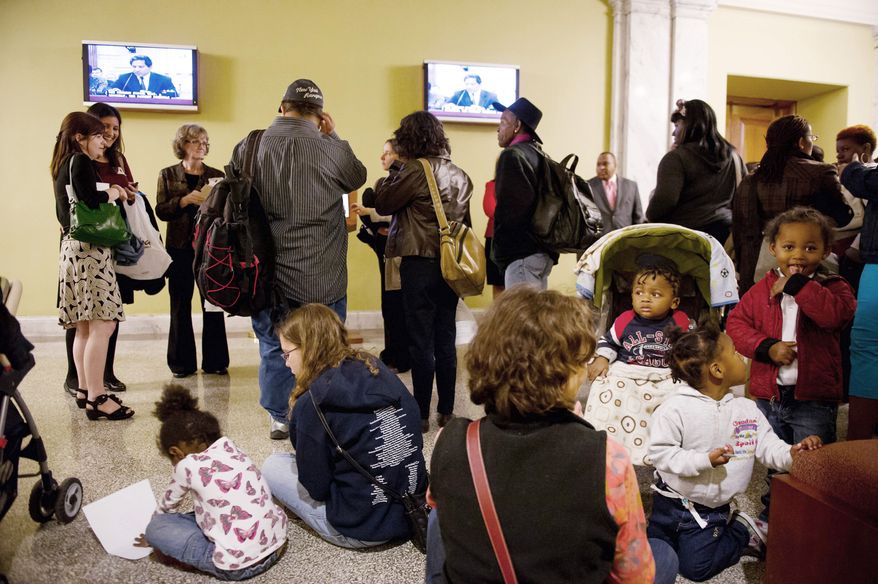 Homeless families gather Monday outside the D.C. Council chamber after disrupting a public budget hearing to demand funds for homeless services. Inside, council member Jim Graham, Ward 1 Democrat, challenges bar and nightclub owners testifying in favor of extending their hours of operation. (Andrew Harnik/The Washington Times)