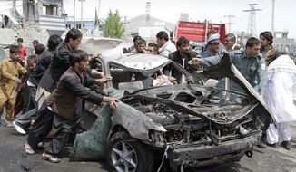 ** FILE ** Afghans push a damaged car from the scene of a militant attack by a suicide car bomber and Taliban militants disguised in burqas in Kabul, Afghanistan, on Wednesday, May 2, 2012. (AP Photo/Ahmad Jamshid)