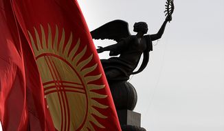 **FILE** The Kyrgyz national flag flies at half staff April 9, 2010, in front of the statue of independence on a central square in Bishkek, Kyrgyzstan. (Associated Press)