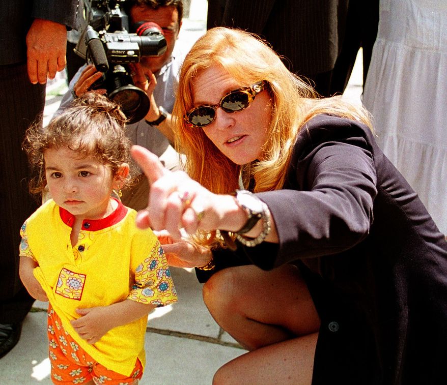 ** FILE ** In this Thursday, June 11, 1998, file photo Britain's Duchess of York Sarah Ferguson points at the cameras as she kneels beside a Turkish child during her visit to the Blue Mosque in Istanbul. (AP Photo/Murad Sezer, File)