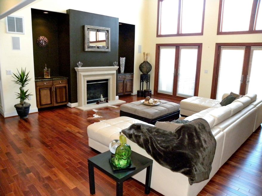 The great room features two sets of French doors and a fireplace flanked by a pair of cabinets with marble counters.