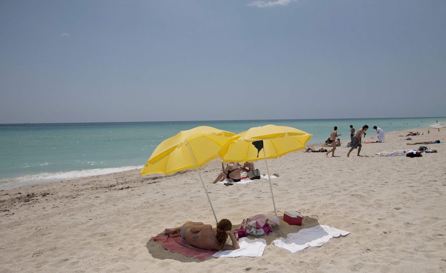 In this Wednesday, May 9, 2012, photo, a sun bather lies under umbrellas on Miami Beach, Fla. In a study released Thursday, May 10, 2012, the Centers for Disease Control and Prevention says half of adults under 30 say they've had a sunburn at least once in the past year. (AP Photo/J. Pat Carter)