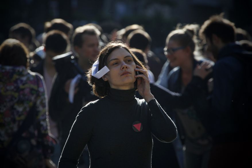 A young Russian woman with a white ribbon — a symbol of protest — speaks on her phone May 10, 2012, as she attends a group of protesters gathering at the Chistiye Prudy, or Clean Ponds, where they vowed to continue their roving protest in Moscow. (Associated Press)
