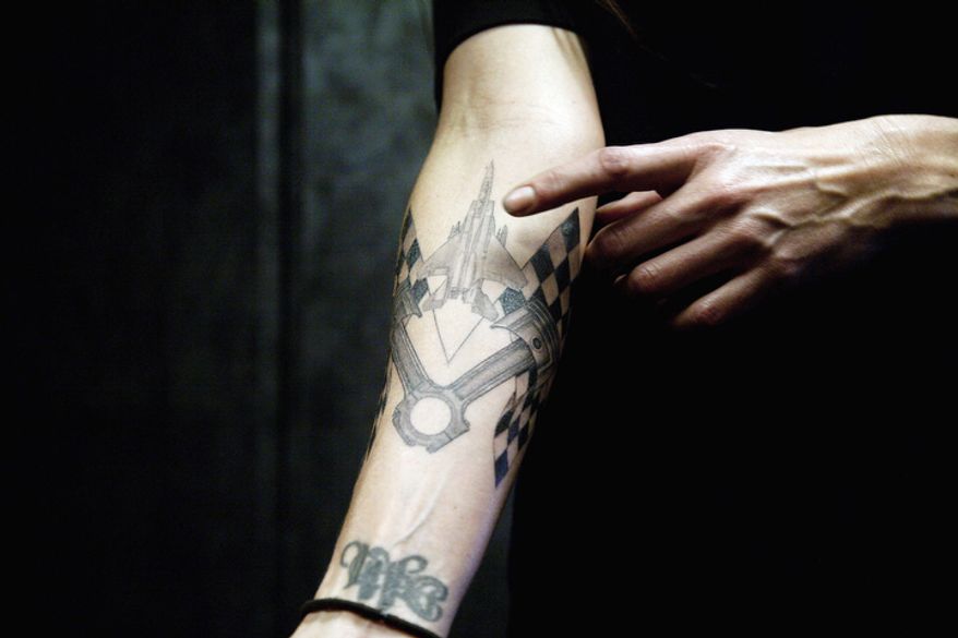 Alexis DeJoria shows some of her tattoos as she prepares for a race at a racetrack in Jupiter, Fla. (AP Photo/J Pat Carter)