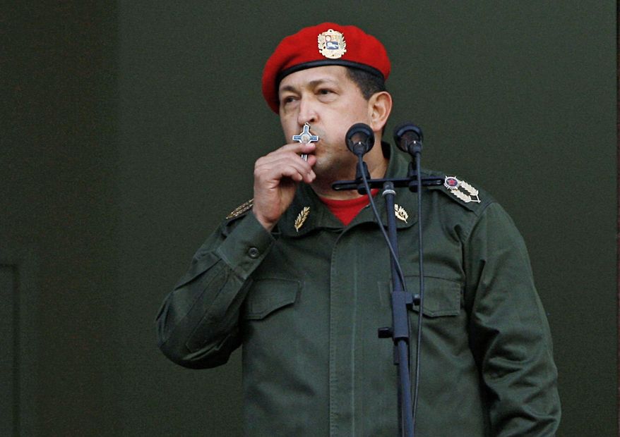 FILE - In this July 4, 2011 file photo, Venezuela's President Hugo Chavez kisses a crucifix as he greets supporters from a balcony in Miraflores presidential palace, after returning from Cuba where he underwent cancer surgery, in Caracas, Venezuela. Chavez has spent much of his career praising the socialist ideas of famed atheists such as Karl Marx and Fidel Castro. However, now in the thick of a prolonged battle against cancer, Chavez is drawing inspiration more than ever from Jesus Christ. (AP Photo/Ariana Cubillos, File)