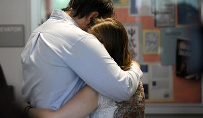 Ken Lewis (left) hugs Allison Schmitt following a vigil for University of West Georgia student Aimee Copeland on May 10, 2012, in Melson Hall on the campus of the University of West Georgia in Carrollton, Ga. Doctors say Copeland, who is fighting a flesh-decaying bacteria she contracted after a zip line accident, will lose her hands and remaining foot to the infection. (Associated Press/Times-Georgian)