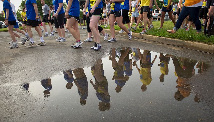 Runners are seen in a puddle from previous rains as they make their way to the starting line for the ACLI Capital Challenge at Anacostia Park in Washington, D.C., Wednesday, May 16, 2012. This is the 31st running of the three-mile race where members of Congress, national media outlets and locals take part in this fundraising event in the early morning hours along the water of the Anacostia River. (Rod Lamkey Jr/The Washington Times)