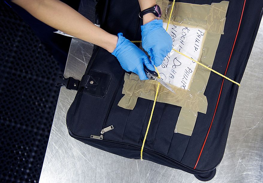 A Customs and Border Protection officer uses a knife to cut through a rope that someone has tied around a suitcase at Washington Dulles International Airport on Thursday, Feb. 16, 2012. CBP officers only open the bags if something has appeared suspicious on the X-ray machine. (Barbara L. Salisbury/The Washington Times)