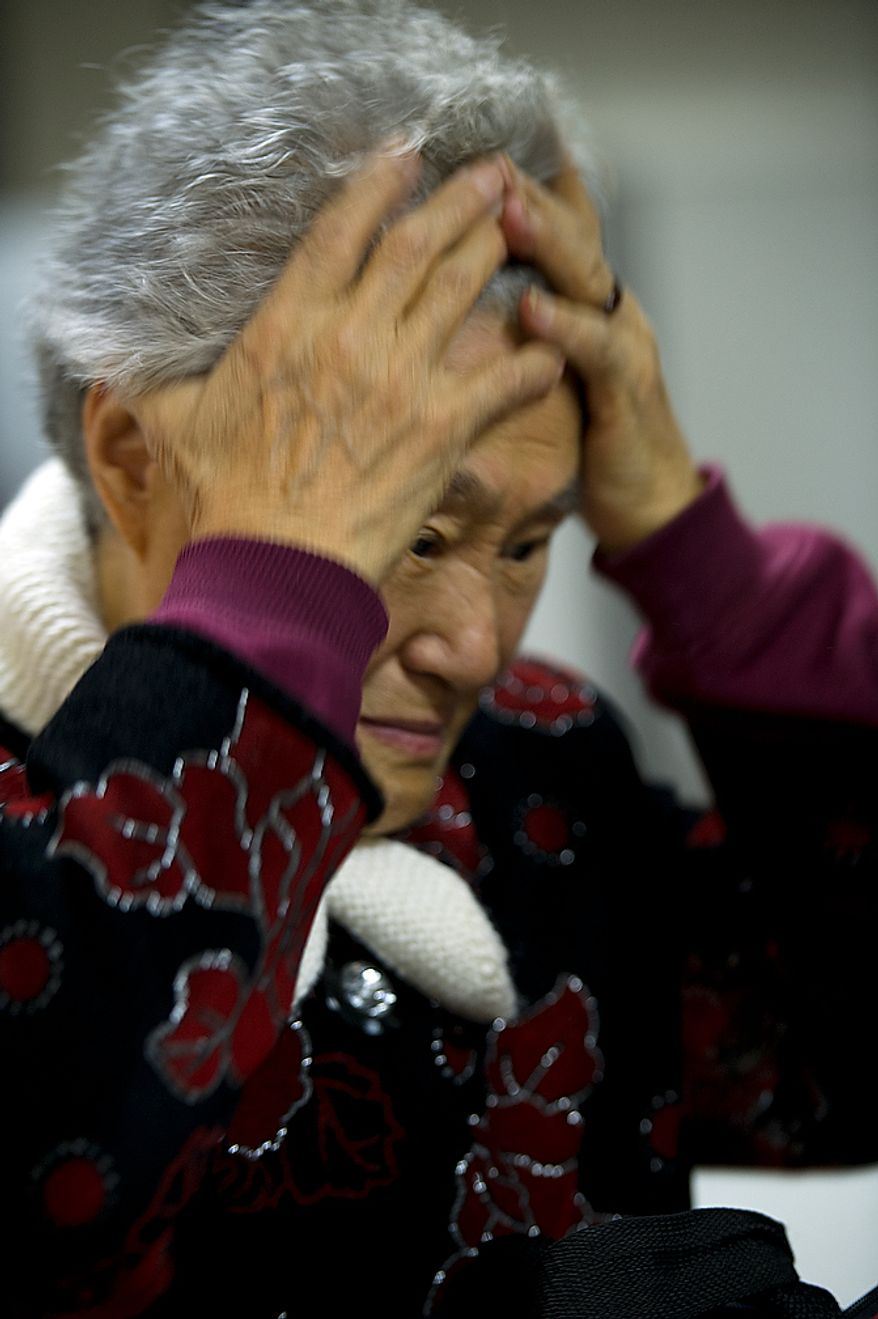 A woman on a flight from Beijing reacts as Customs and Border Protection officers go through her bag at Washington Dulles International Airport on Thursday, Feb. 16, 2012. Officers must seize and destroy any items that are illegal to bring into the United States, such as certain fresh fruits, meat products and plant life. (Barbara L. Salisbury/The Washington Times)