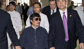 ** FILE ** In this file photo taken Wednesday, May 2, 2012, and released by the U.S. Embassy Beijing Press Office, blind activist Chen Guangcheng, center, holds hands with U.S. Ambassador to China, Gary Locke, at a hospital in Beijing. (AP Photo/U.S. Embassy Beijing Press Office, File)