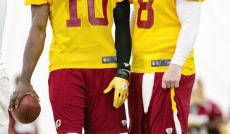 Redskins rookie quarterback Robert Griffin III (10) and Rex Grossman, the starter for most of the 2011 season, share a moment during the first organized team activity. Griffin was the Heisman Trophy winner last year at Baylor. (Andrew Harnik/The Washington Times)