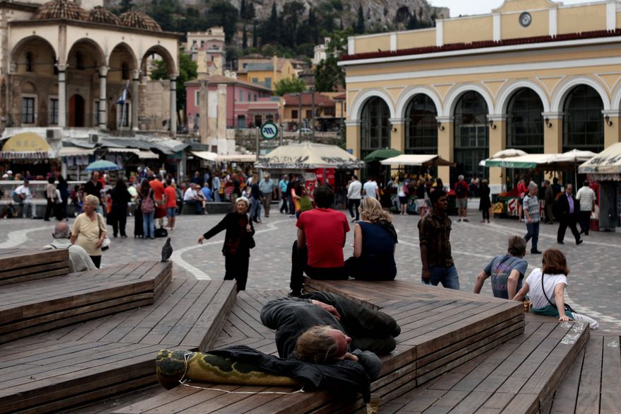 ** FILE ** A man sleeps at Monastiraki Square in central Athens in May, 2012. Homelessness, the most visible sign of Greece's financial despair, has risen by around 25 percent, according to estimates by a state-funded relief agency. (Associated Press)