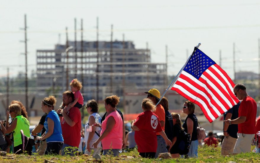 The ruins of the tornado damaged St. John's Regional Medical center stands in the distance as people walk the path of destruction. (AP Photo/Charlie Riedel)