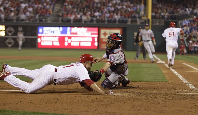 Washington Nationals catcher Jesus Flores, right, tags out Philadelphia Phillies&#x27; Placido Polanco at home after Polanco tried to score on fielder&#x27;s choice by Philadelphia Phillies&#x27; Carlos Ruiz in the sixth inning of a baseball game, Monday, May 21, 2012, in Philadelphia. (AP Photo/Matt Slocum)