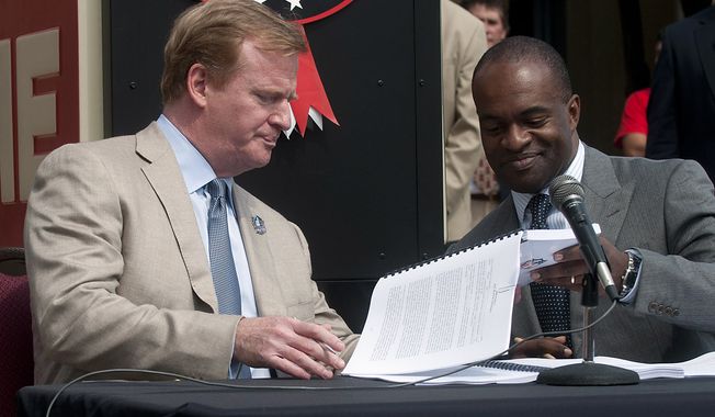 **FILE** NFL Commissioner Roger Goodell (left) and NFLPA Executive Director Demaurice Smith exchange papers Aug. 5, 2011, as they sign their collective bargaining agreement at the Pro Football Hall of Fame in Canton, Ohio. (Associated Press)