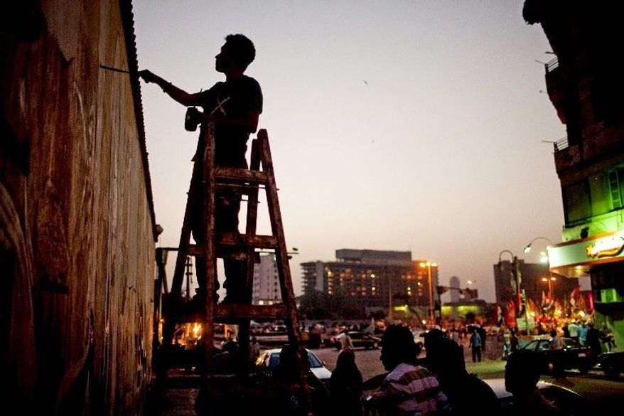 A political activist paints a mural on a wall Thursday in Cairo's Tahrir Square. During the uprising that resulted in the ouster of President Hosni Mubarak in 2011, Tahrir Square was the central gathering point for protesters. Since the revolution, many streets leading to the square display murals dedicated to the uprising and those who died in it. (Associated Press)