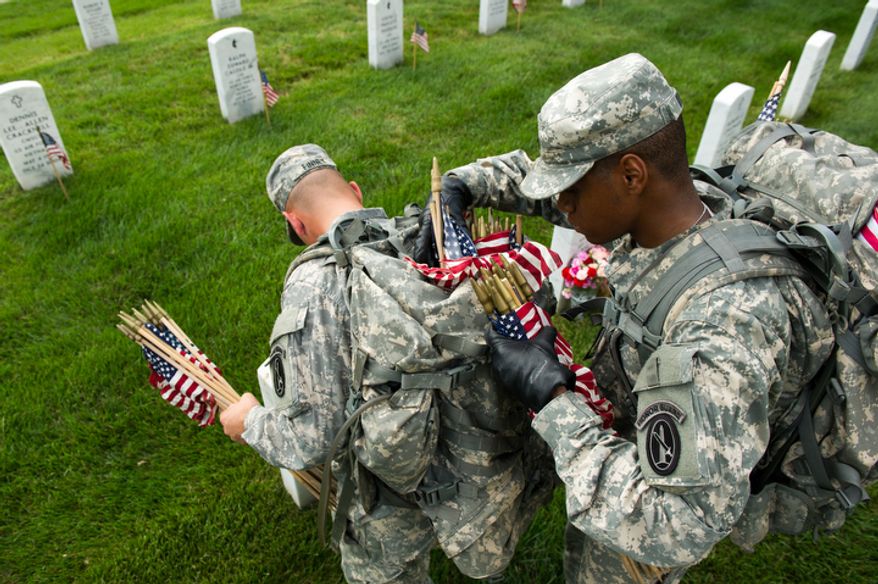 Spc. John Finney, left, and Spc. Kevin Wilson, right, and other Honor Guard soldiers place small America flags at each grave to honor the nation's fallen service members. (Andrew Harnik/The Washington Times)