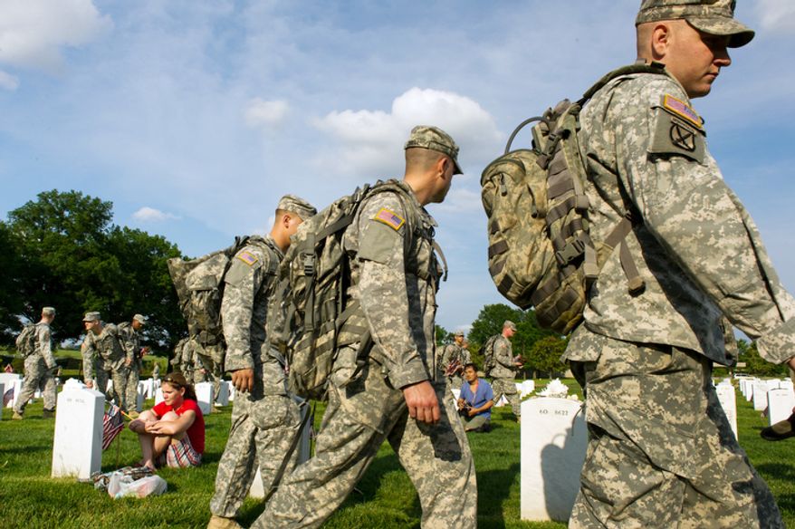 Honor Guard soldiers place American flags at each grave at Arlington National Cemetery to honor the nation's fallen service members as Air Force Maj. Terry Dutcher (left), based at Hill Air Force Base in Utah, cries at the grave of her son, Army Cpl. Michael Avery Pursel, 19, who was killed in Iraq in 2007, Arlington, Va., Thursday, May 24, 2012. (Andrew Harnik/The Washington Times)
