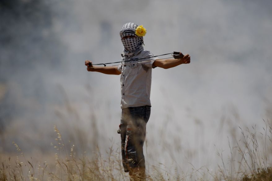 A Palestinian demonstrator prepares to hurl a stone toward Israeli troops during a protest May 25, 2012, against the expansion of the nearby Jewish settlement of Halamish in the West Bank village of Nabi Saleh, near Ramallah. (Associated Press)