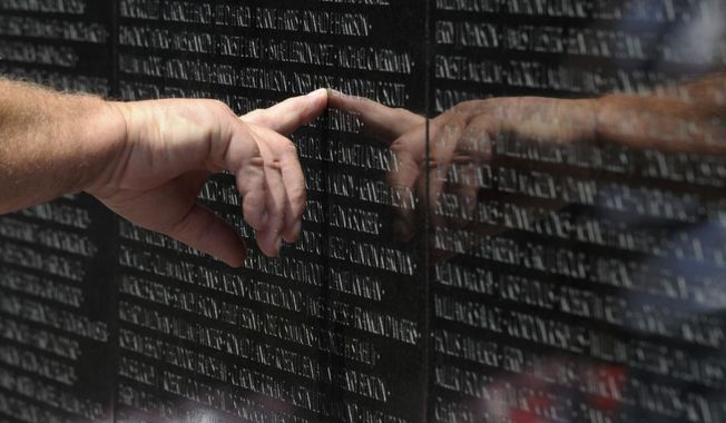 A visitor to the Vietnam Veterans Memorial touches the name of a fallen soldier etched on the wall of the memorial in Washington, Friday, May 25, 2012. (AP Photo/Susan Walsh)