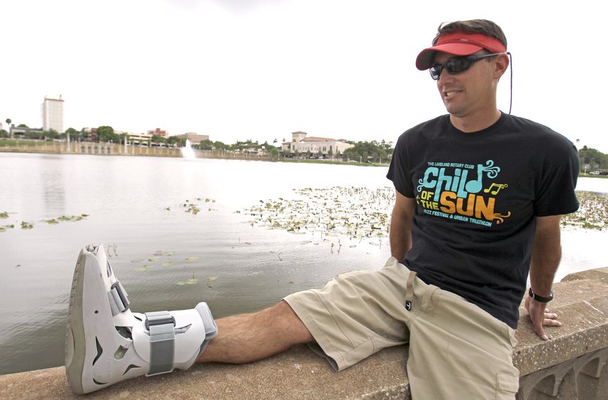 Greg Farris takes a break while wearing a protective boot as he helps set up for an April weekend triathlon event in Lakeland, Fla. Farris injured his foot while running in barefoot running shoes.(AP Photo/John Raoux)