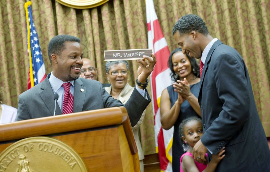 D.C. Council Chairman Kwame R. Brown holds up the new "Mr. McDuffie" nameplate for Kenyan McDuffie, the newest member of the D.C. Council who was sworn in Wednesday. With Mr. McDuffie are his wife, Princess, and daughter Jozi. "I know where we are today, but I also know how far we have to go," the new Ward 5 member said upon taking over for his convicted predecessor Harry Thomas Jr. (Barbara L. Salisbury/The Washington Times)