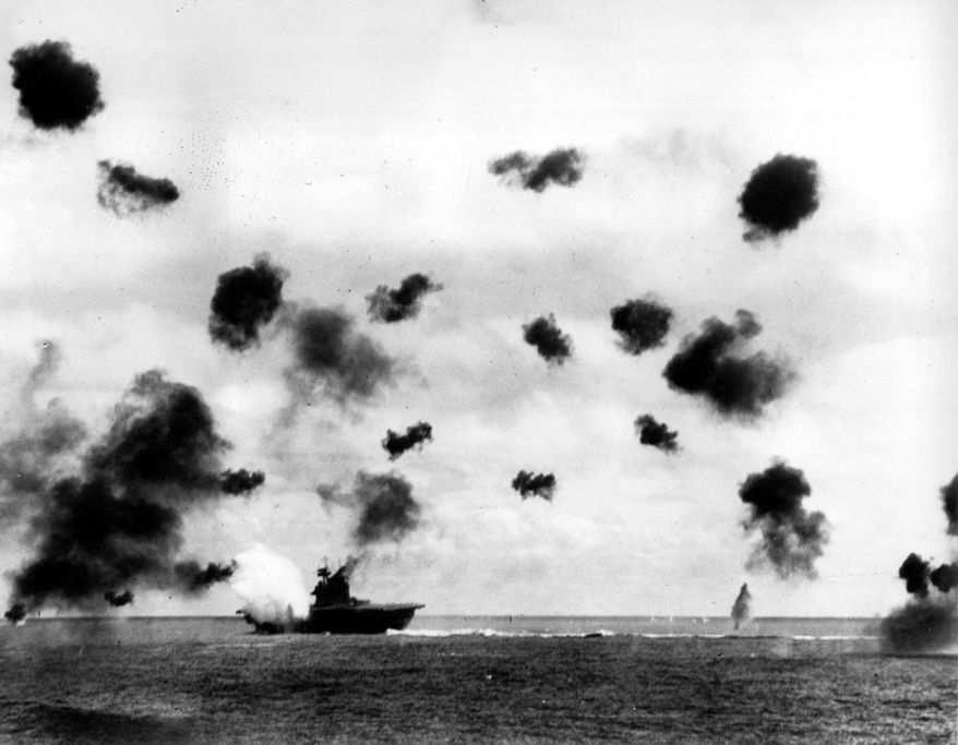 Smoke rises from the USS Yorktown after a Japanese bomber hit the aircraft carrier in the Battle of Midway near the Midway Islands in June 1942 during World War II. Bursts from anti-aircraft fire fill the air. (Associated Press/U.S. Navy)